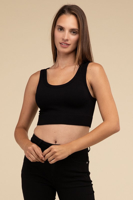 A person with long brown hair wearing the Ribbed Seamless Crop Top in light blue and black pants stands against a beige background, showcasing a perfect summer essential.