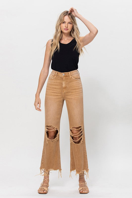 A person wearing 90's Vintage Crop Flare in a brown color and strappy sandals, standing against a plain background.