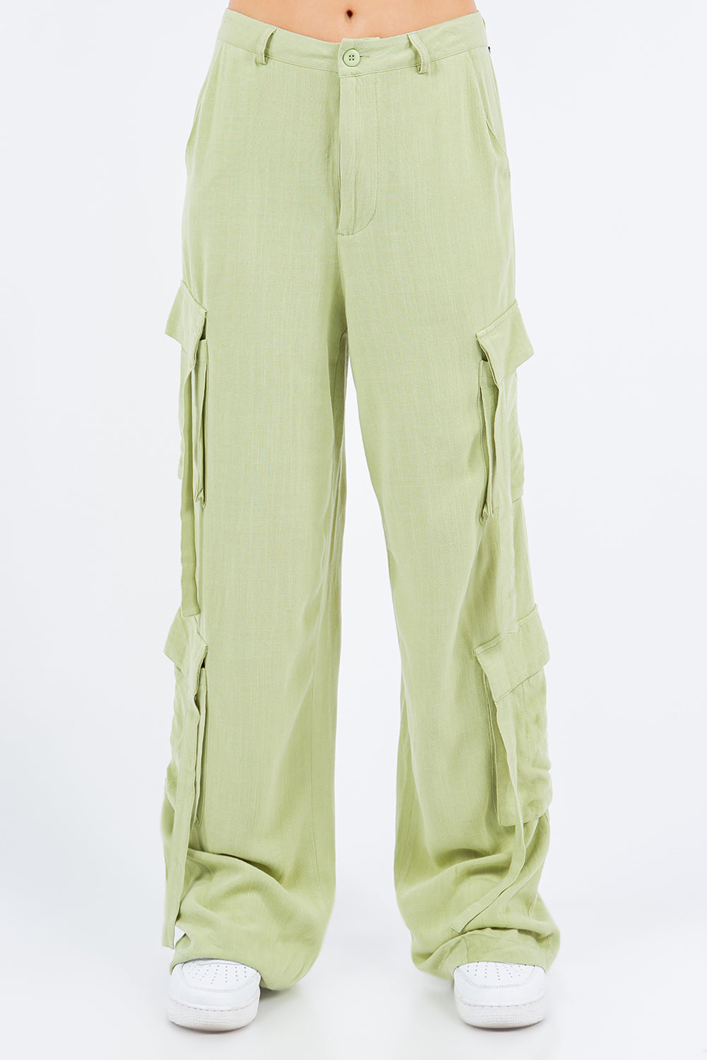 A person is wearing American Bazi light green linen wide leg cargo pants with multiple pockets and white sneakers.