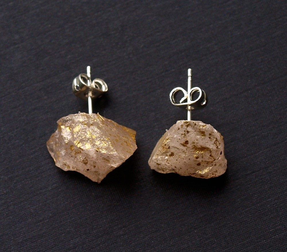 A pair of Gold Splatter & Raw Rose Quartz Chunk Earrings, featuring unpolished stones on silver posts, elegantly displayed on a dark surface.