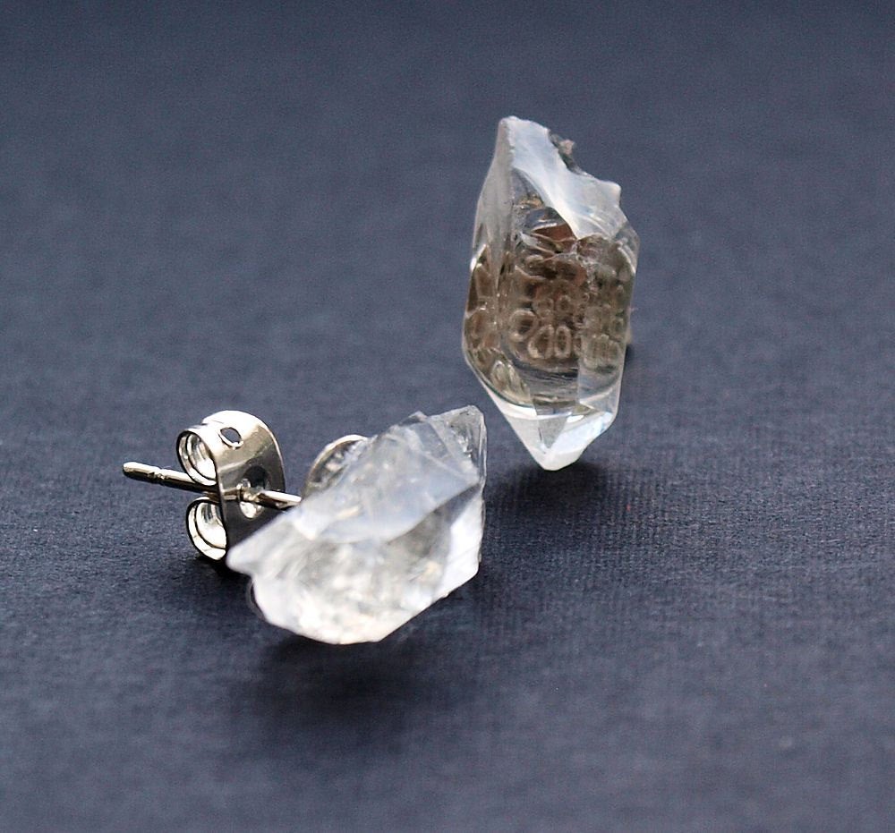 Close-up of a striking pair from the Raw Quartz Chunk Earrings collection, showcasing rough, clear quartz stones set in silver on a dark surface, they make a statement in any collection.