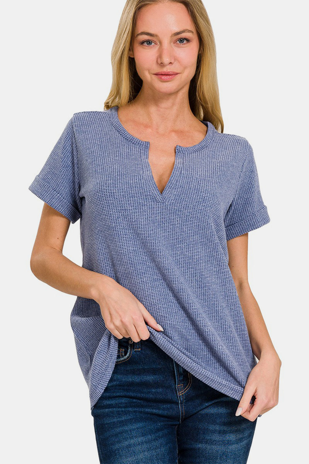 A person wearing a Zenana Notched Short Sleeve Waffle T-Shirt in blue and jeans stands against a plain background, capturing the essence of a casual wardrobe.