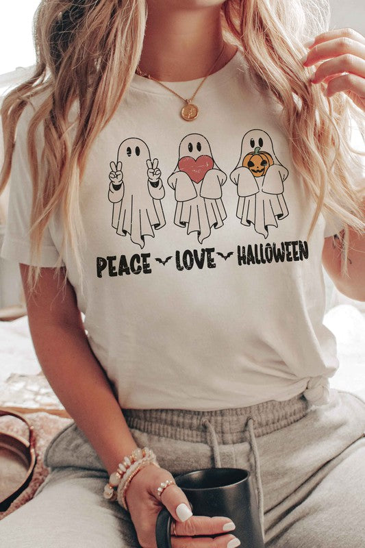 A person wearing the PEACE LOVE HALLOWEEN Graphic Tee, which features three cartoon ghosts—one making a peace sign, another holding a heart, and the third with a pumpkin—along with the words "PEACE LOVE HALLOWEEN" printed underneath.