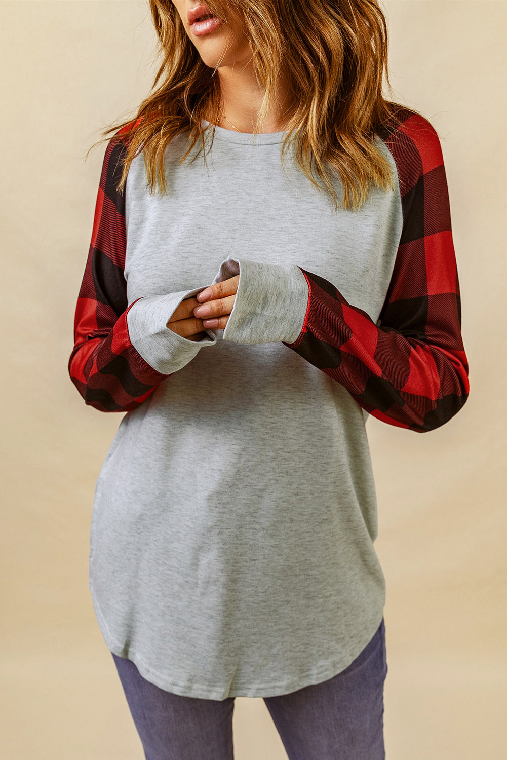 A person with wavy, brown hair is standing with their back to the camera, wearing a Gray Buffalo Plaid Long Sleeve Sweatshirt and blue jeans.