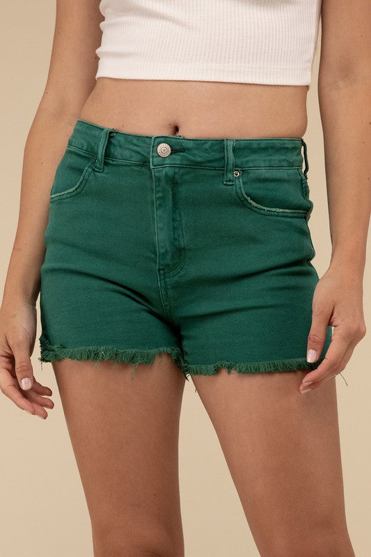 A person wearing green Acid Washed Frayed Cutoff Hem Shorts, holding the hem. Only the torso and thighs are visible.