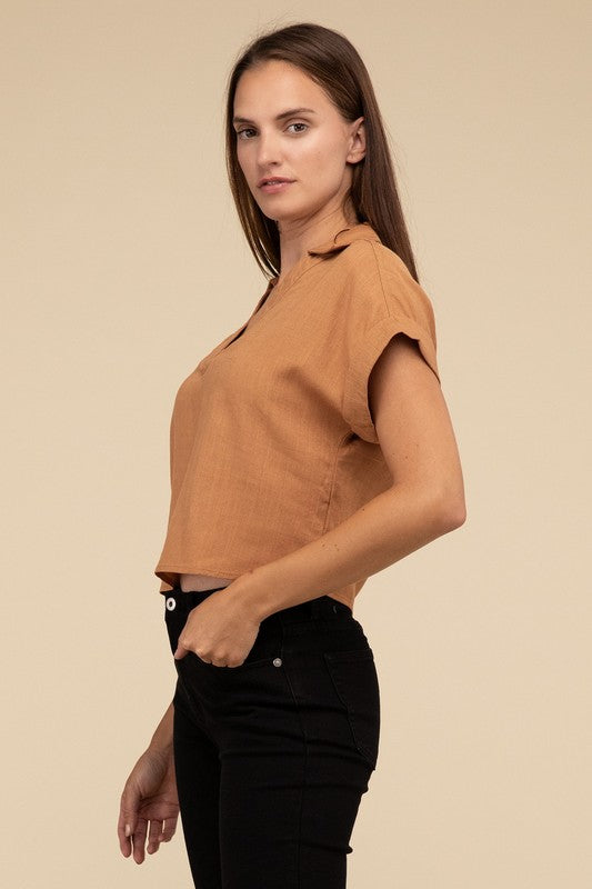 A woman with long hair is wearing the Always a Delight Short Sleeve Linen Top in brown and black pants, standing against a beige background.