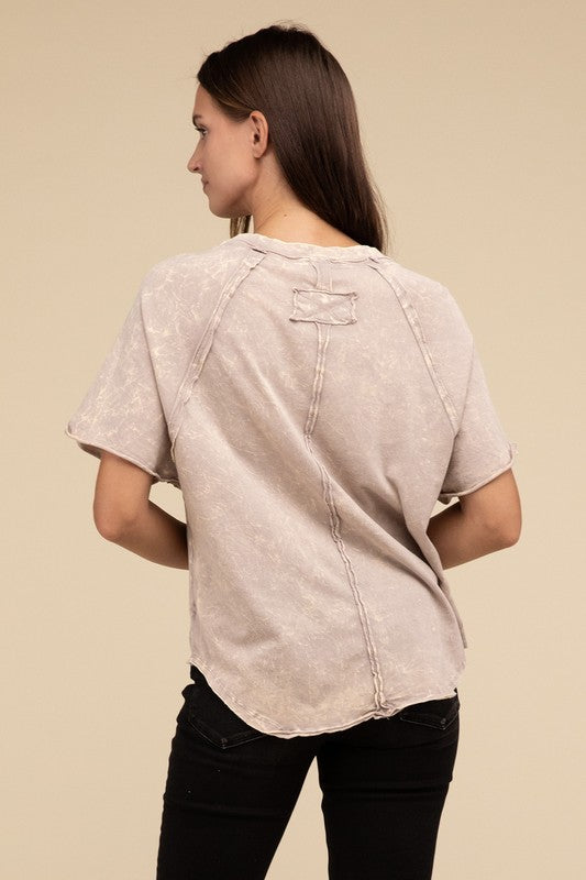 A person with long brown hair wearing a Back Patch Crinkle Washed Raglan Sleeve T-Shirt stands against a plain beige background.