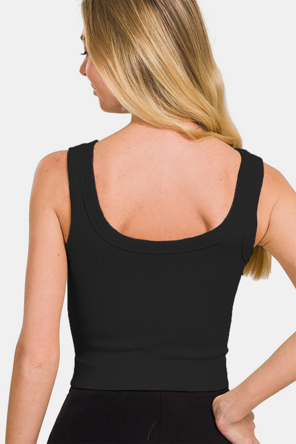 A person wearing the Zenana Ribbed Round Neck Cropped Tank in black stands against a white background, looking at the camera with a neutral expression—an ideal addition to any summer wardrobe.