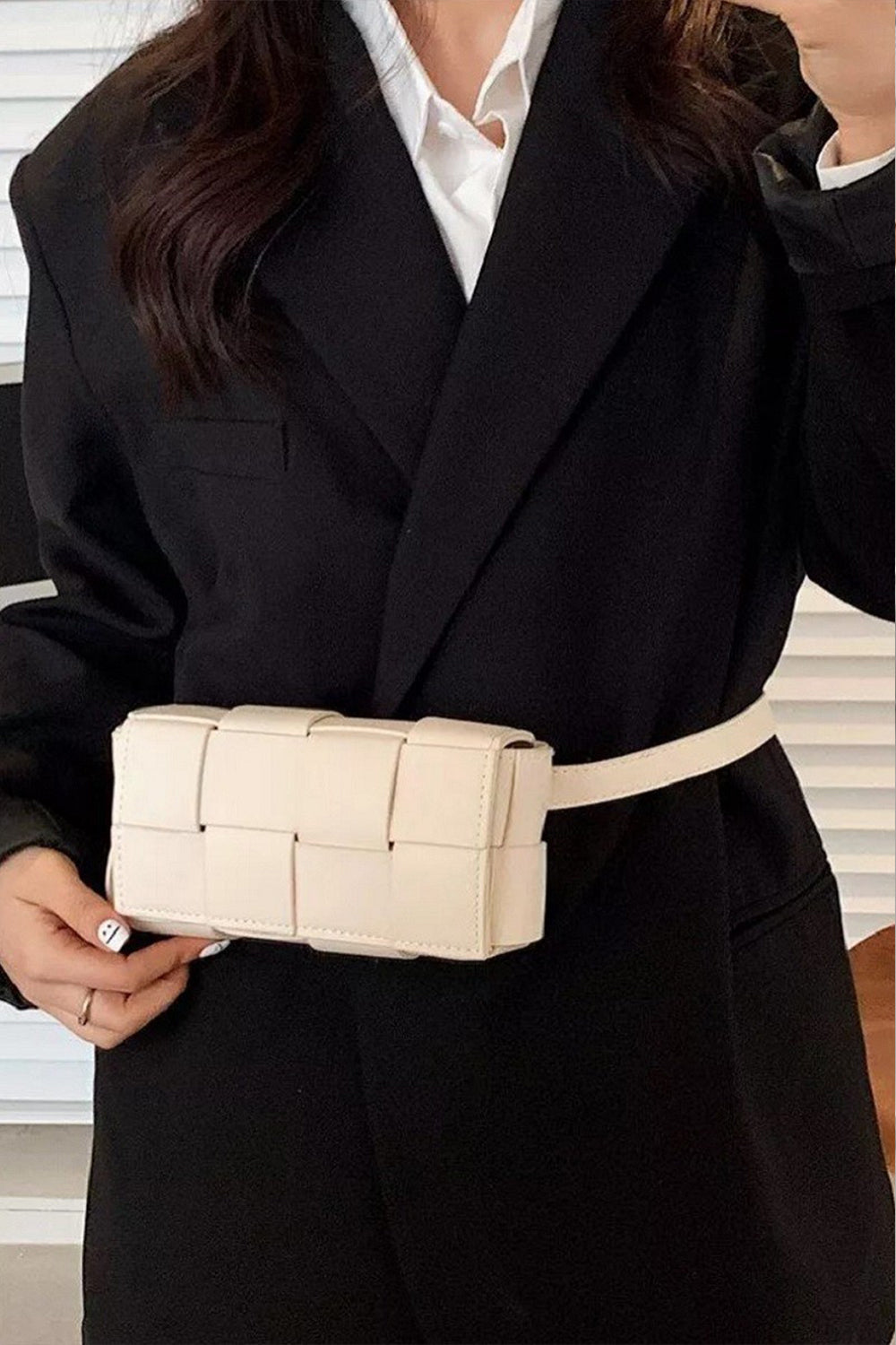 Person wearing a white button-up shirt and holding a black Zenana Vegan Leather Woven Crossbody Bag.