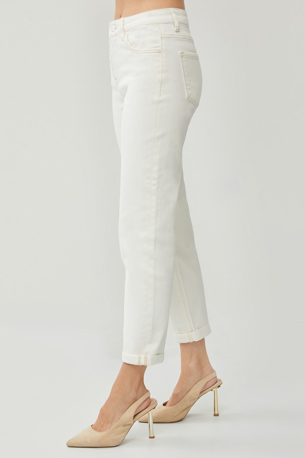 Description: Person wearing RISEN Full Size High Waist Rolled Hem Straight Jeans in white with beige heels against a plain background. 