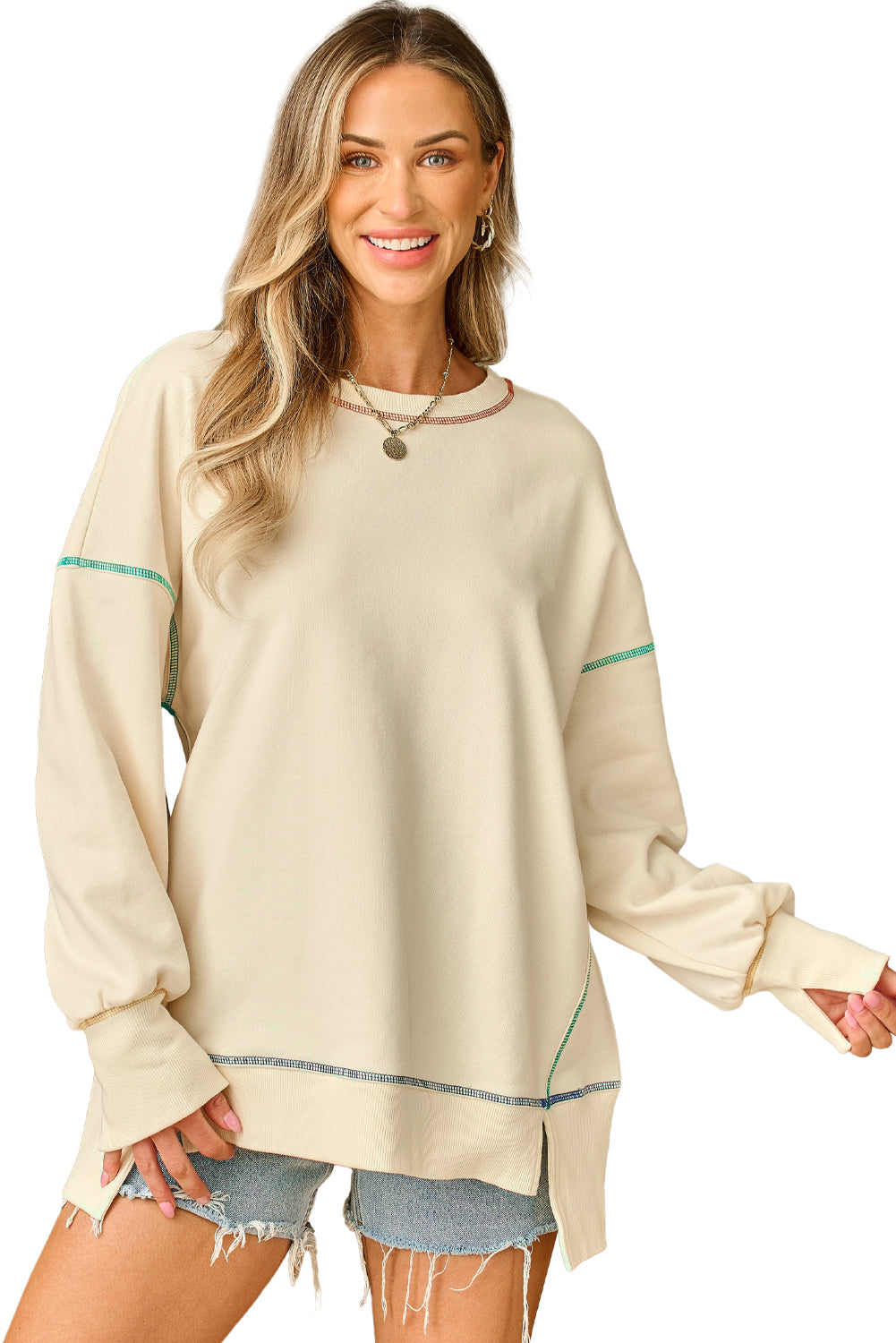 A woman with blonde hair is facing away, wearing a Contrast Stitching Split Baggy Sweatshirt. She stands in a room adorned with plants and wooden furniture in the background.