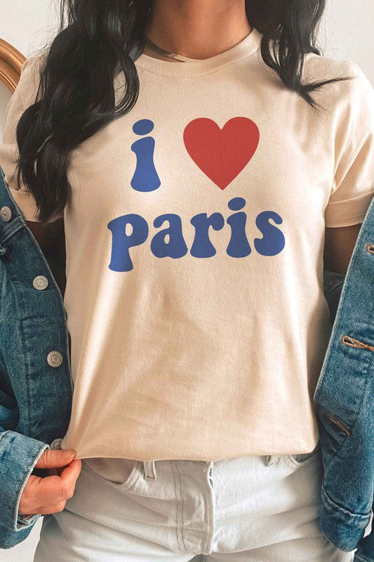 Person wearing a unisex "I LOVE PARIS" graphic tee made from 100% Airlume combed and ringspun cotton, high-waisted denim shorts, and a yellow knit sweater draped over their arms.