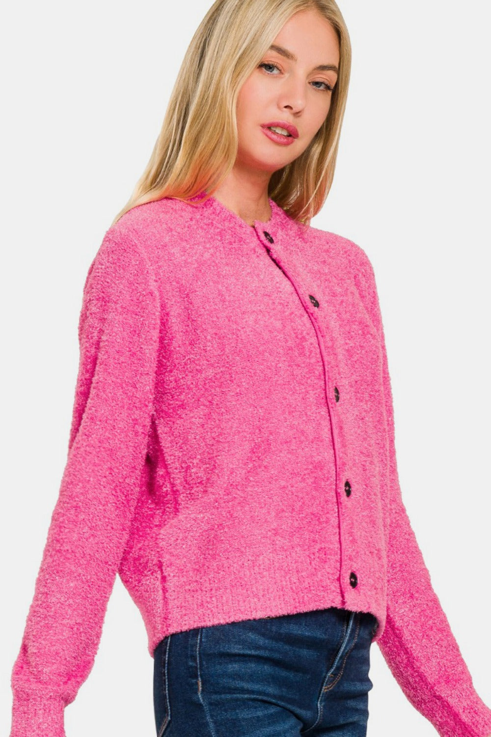 A person with long blonde hair wears a Zenana Button Down Long Sleeve Sweater Cardigan in bright pink and dark blue jeans, posing against a plain white background.