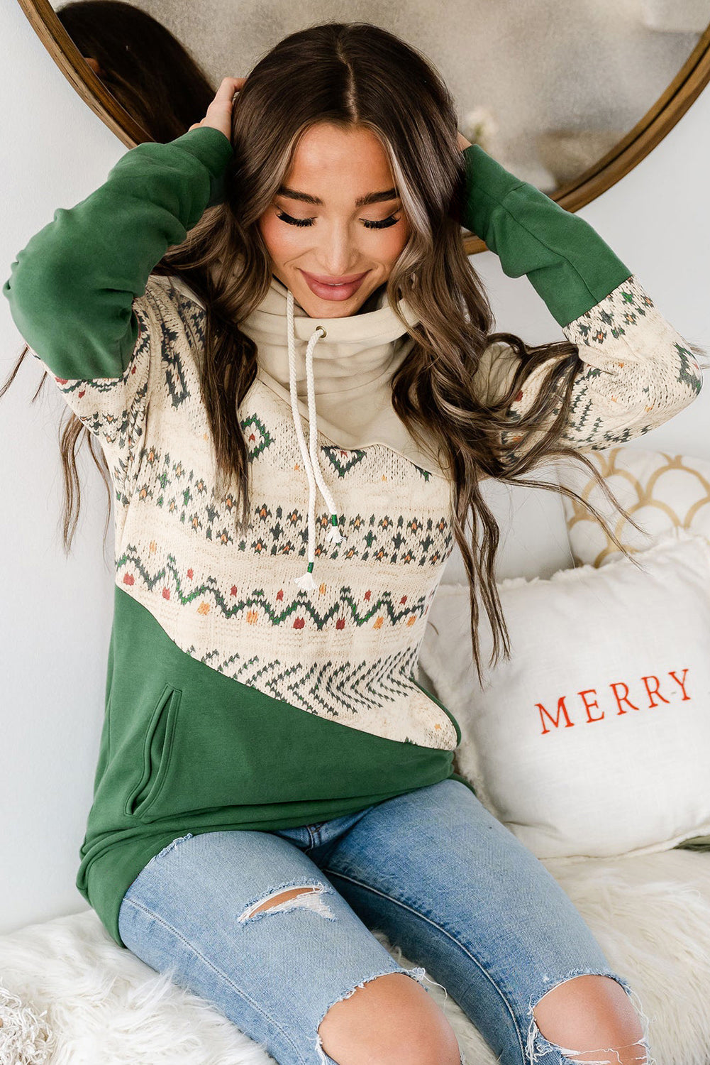 A person with long, wavy hair is seen from the back, wearing a Blackish Green Geometric Color Block Patchwork Hoodie and blue jeans, carrying a brown crossbody bag.