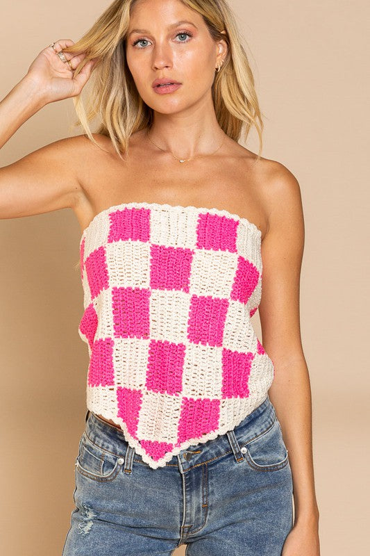 A woman stands against a beige background, wearing the playful Checkerboard Pattern Tube Top Sweater in pink and white, which beautifully contrasts with her blue jeans.