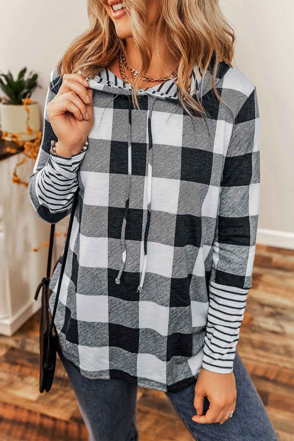 A person with wavy hair wearing a Multicolour Plaid Striped Patchwork Drawstring Hoodie stands indoors, facing away from the camera.