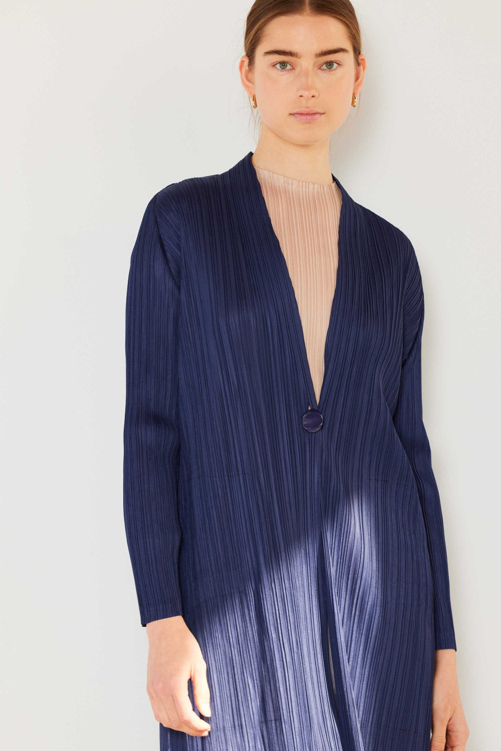 A person wears the Marina West Swim Pleated Long Sleeve Cardigan over a matching top and gray wide-leg pants, standing against a plain light background. This versatile layering piece, with its chic pleated long sleeves, adds an elegant touch to the ensemble.