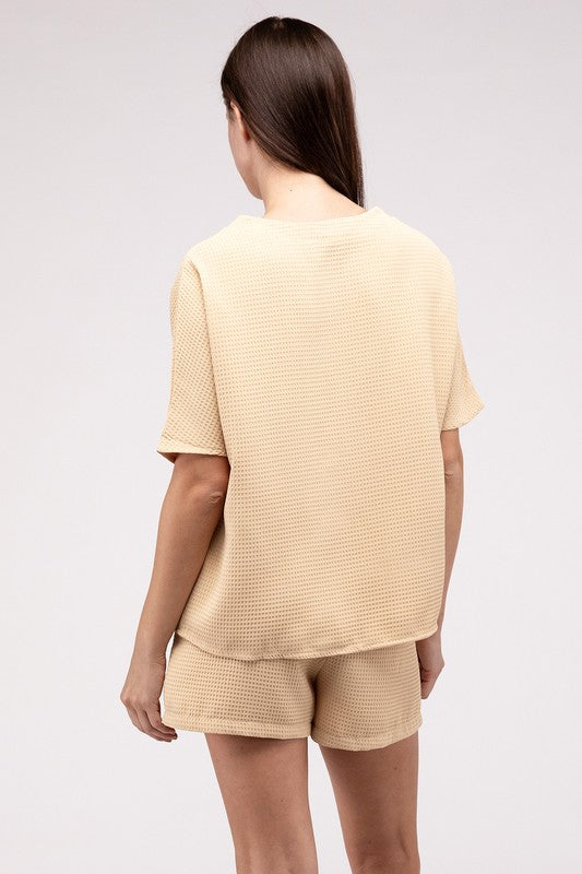 Clad in the Waffle Round Neck Top and Short Set paired with black sunglasses, a person stands against a plain beige background, highlighting the non-stretch polyester fabric.