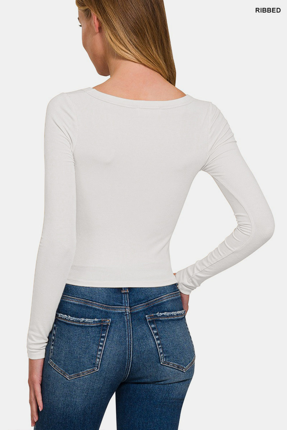 A person with long hair wears a comfortable, stylish Zenana Scoop Neck Long Sleeve T-Shirt in white and blue jeans, standing against a plain background. This versatile wardrobe essential is perfect for any occasion.