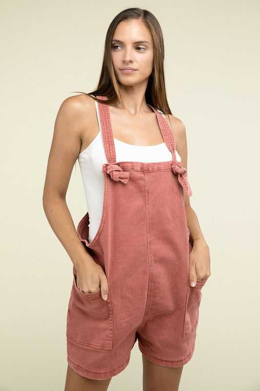 A person wearing the Washed Knot Strap Romper and a white tank top stands against a plain background.