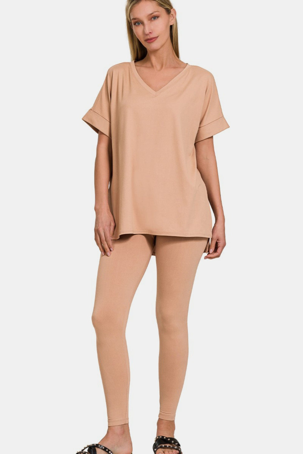 A person wearing the Zenana Full Size V-Neck Rolled Short Sleeve T-Shirt and Leggings Lounge Set in classic beige stands against a plain white background, exuding both comfort and style.