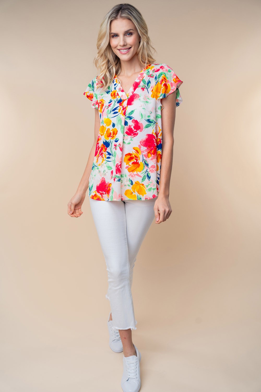 A woman wearing a White Birch Full Size Short Sleeve Floral Woven Top stands against a neutral background.