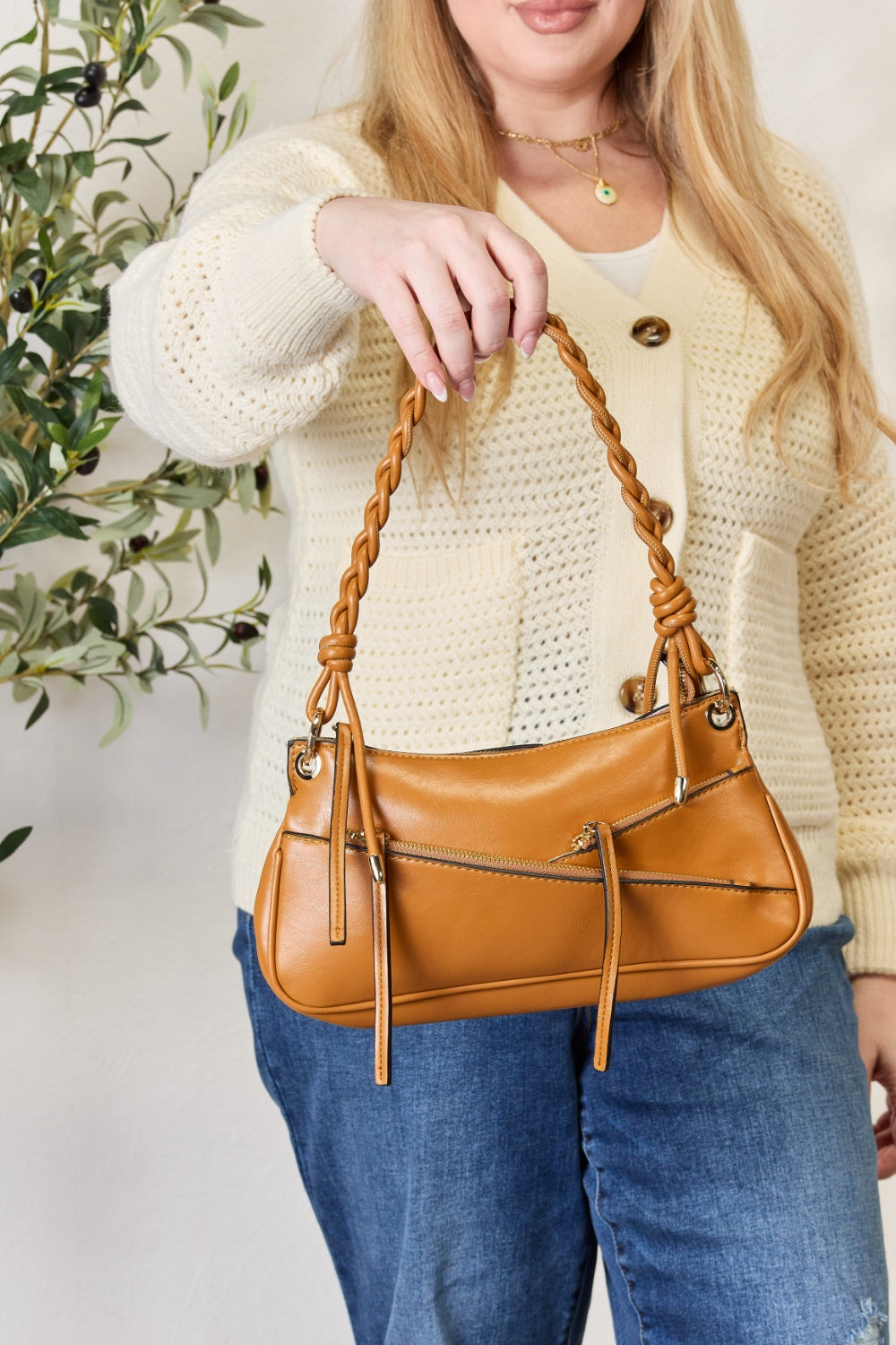 A person exudes bohemian elegance, carrying the SHOMICO Braided Strap Shoulder Bag, expertly crafted with advanced leather techniques and braided handles, while wearing a cream sweater and blue jeans.