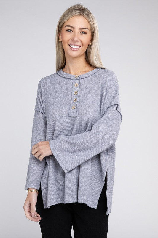 Woman in a blue Ribbed Brushed Melange Hacci Henley sweater with button details posing with her hand on her chin.