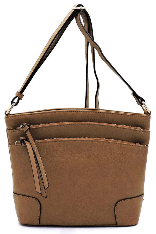 The Fashion Multi Zip Pocket Crossbody Bag is a beige faux leather handbag featuring gold hardware, a front zipper pocket, a two-tone adjustable shoulder strap, and two tassels.