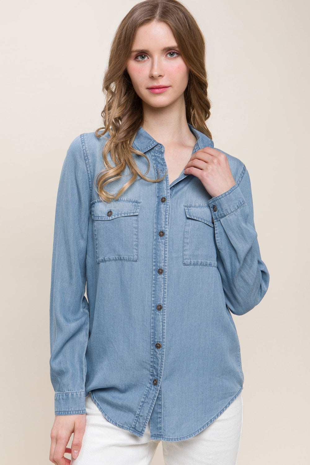 A woman in a Love Tree Scooped Hem Button Up Denim Shirt paired with white pants stands against a neutral background.