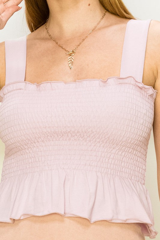 Someone wearing a fashionable Trend Times Smocked Ruffled Crop Top in chic black and a necklace with a leaf pendant. The knit stretch fabric contours their form as they look to the side.