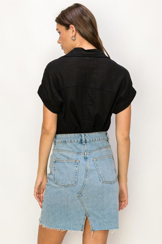 A woman with long hair is wearing the Always a Delight Short Sleeve Linen Top in brown and black pants, standing against a beige background.