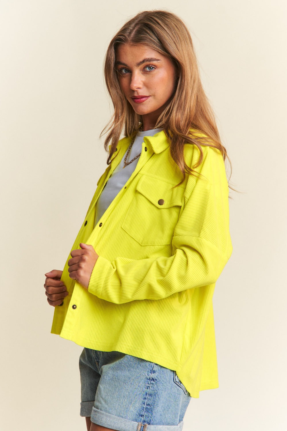 Person wearing a relaxed fit, bright yellow J.NNA Snap Down Long Sleeve High Low Shacket over a white top and denim jeans, smiling against a neutral background.