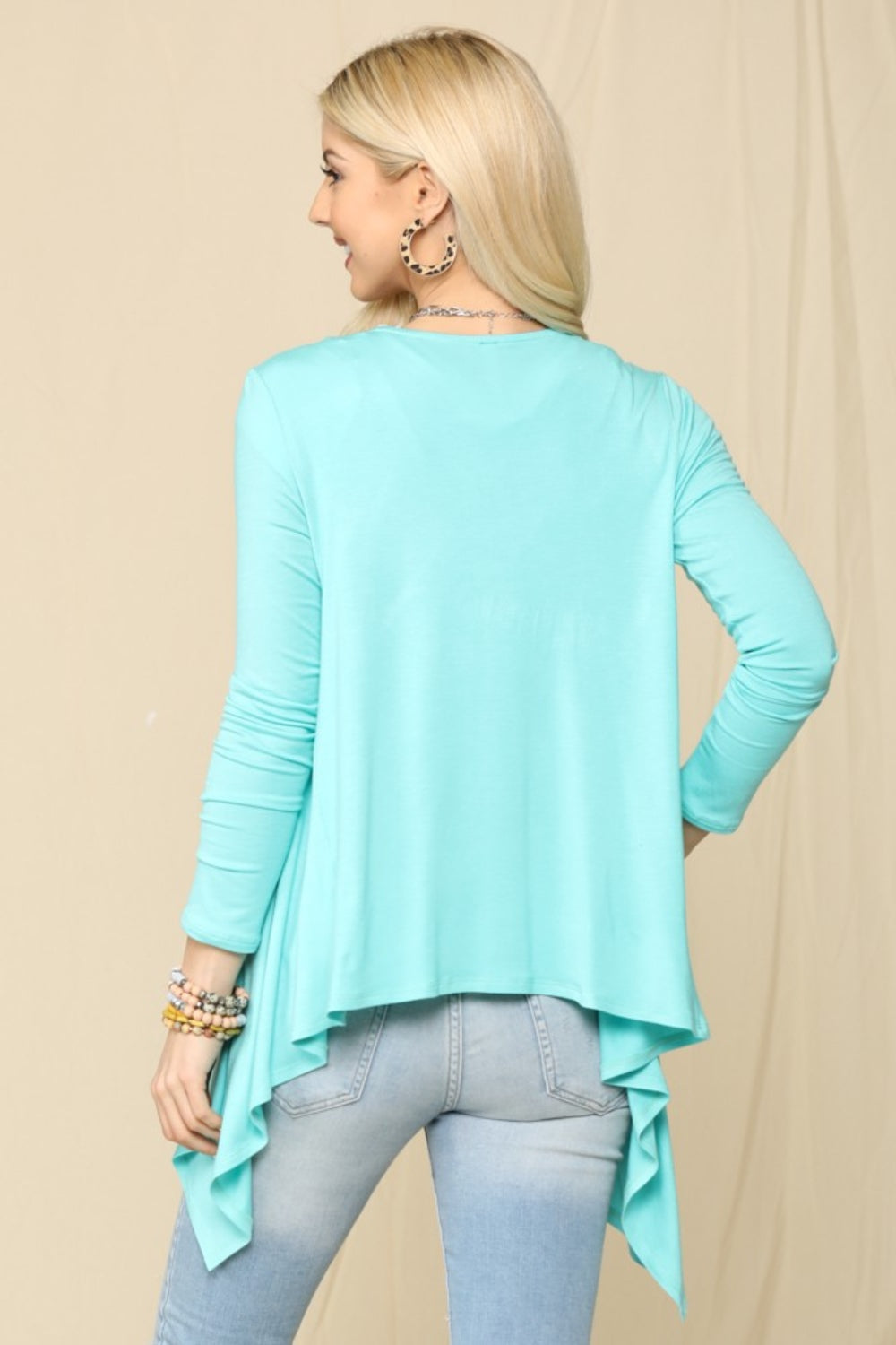 A person is wearing the Celeste Full Size Open Front Knit Cardigan in light blue over a white top and jeans, smiling and standing against a plain background.