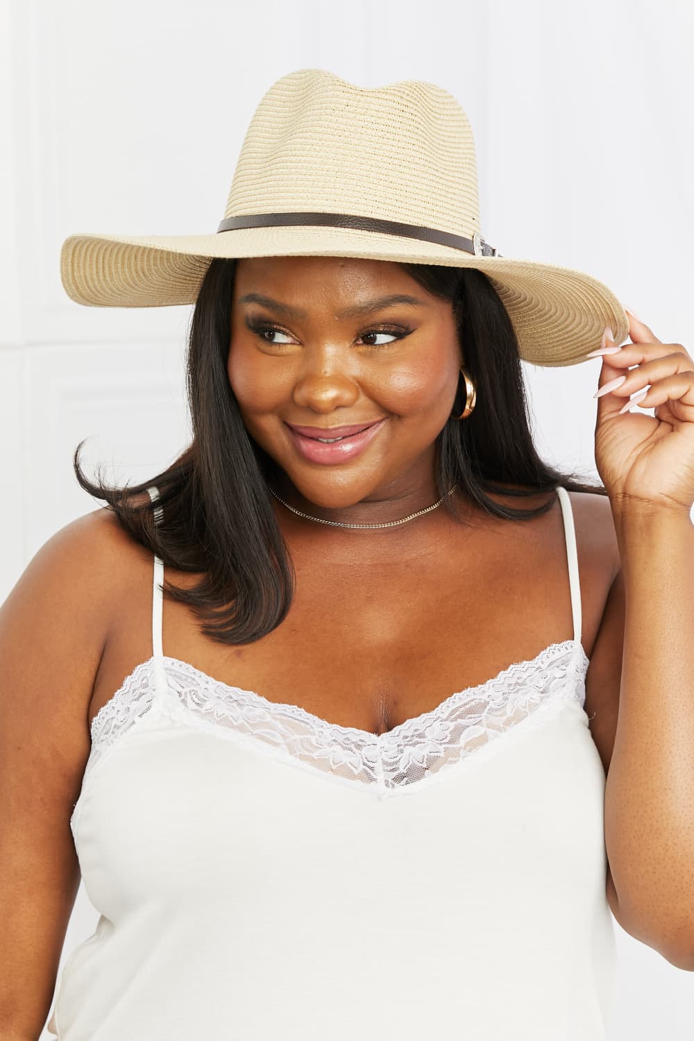 A woman wearing a light-colored tank top and a Fame Boho Summer Straw Fedora Hat with a brown band, smiling and facing slightly to the right.