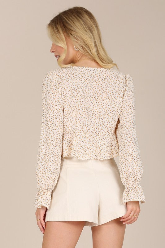 A person wearing an LS floral frill blouse with puff sleeves and beige shorts poses against a neutral background.