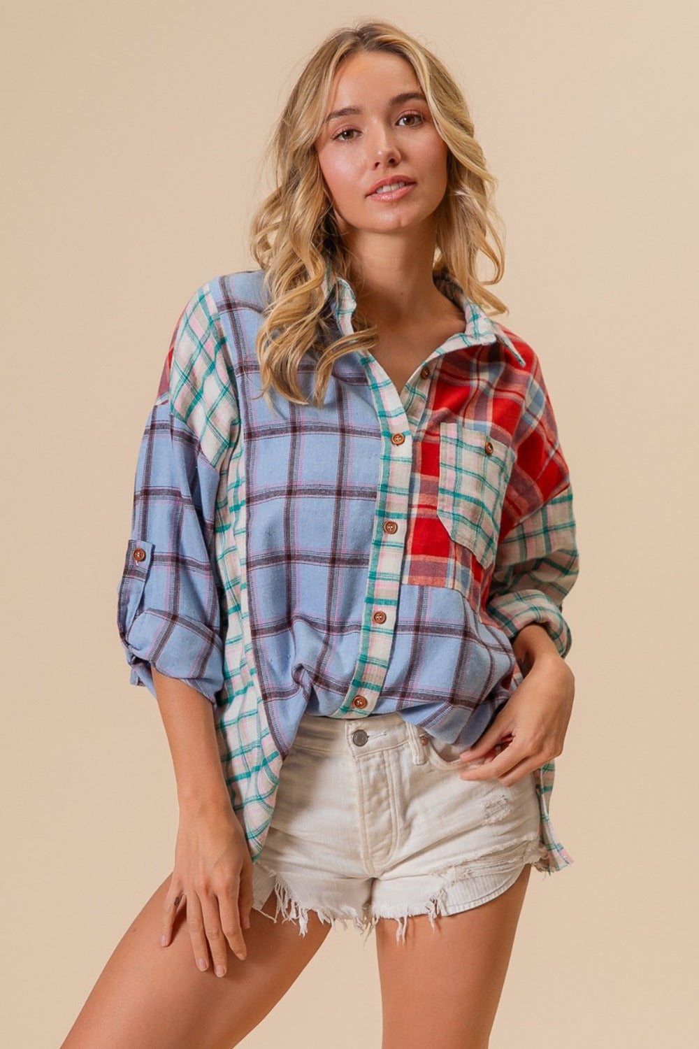 A person wearing a vibrant BiBi Color Block Plaid Button Down Shirt and white denim shorts stands against a neutral background.