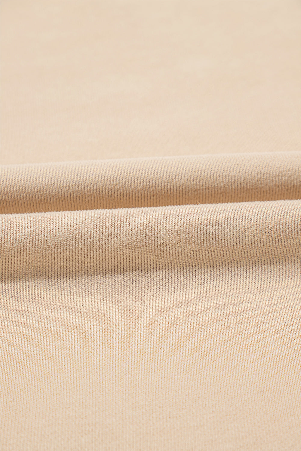 A person with long brown hair is standing with their back to the camera, wearing a Parchment Solid Kangaroo Pocket Half Zipper Oversized Hoodie and black shorts.