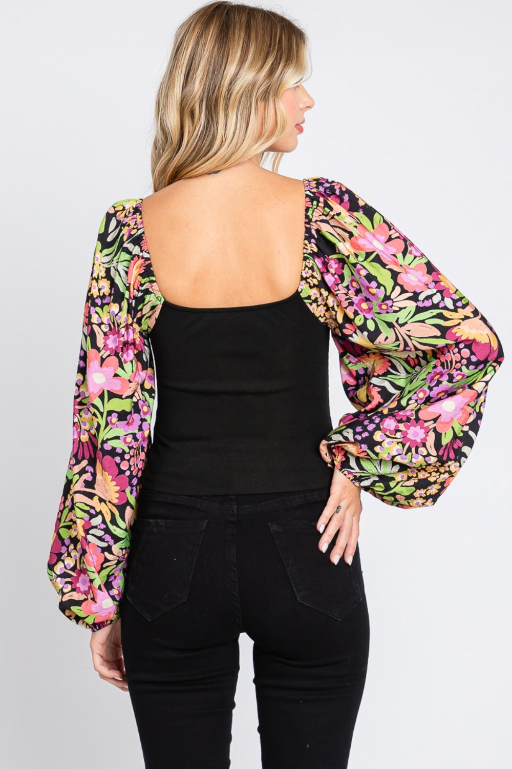 A woman wearing the chic ODDI Full Size Floral Balloon Sleeve Blouse poses against a plain background, showcasing this versatile piece.