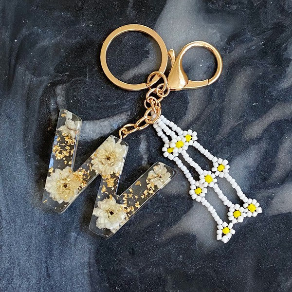 Baby Daisy Initial Key Chain alphabet keychains with real daisy flowers and gold flakes on a marble surface.