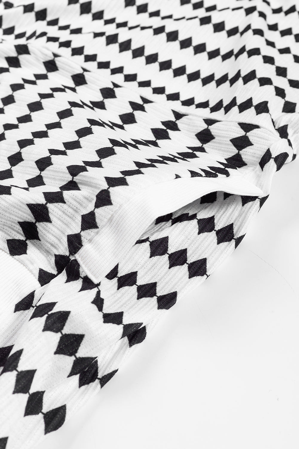 A woman in a Black Stripe Argyle Striped Half Button Oversized Hoodie stands in a room with light green brick walls, a painting of a sailboat, and a fan.