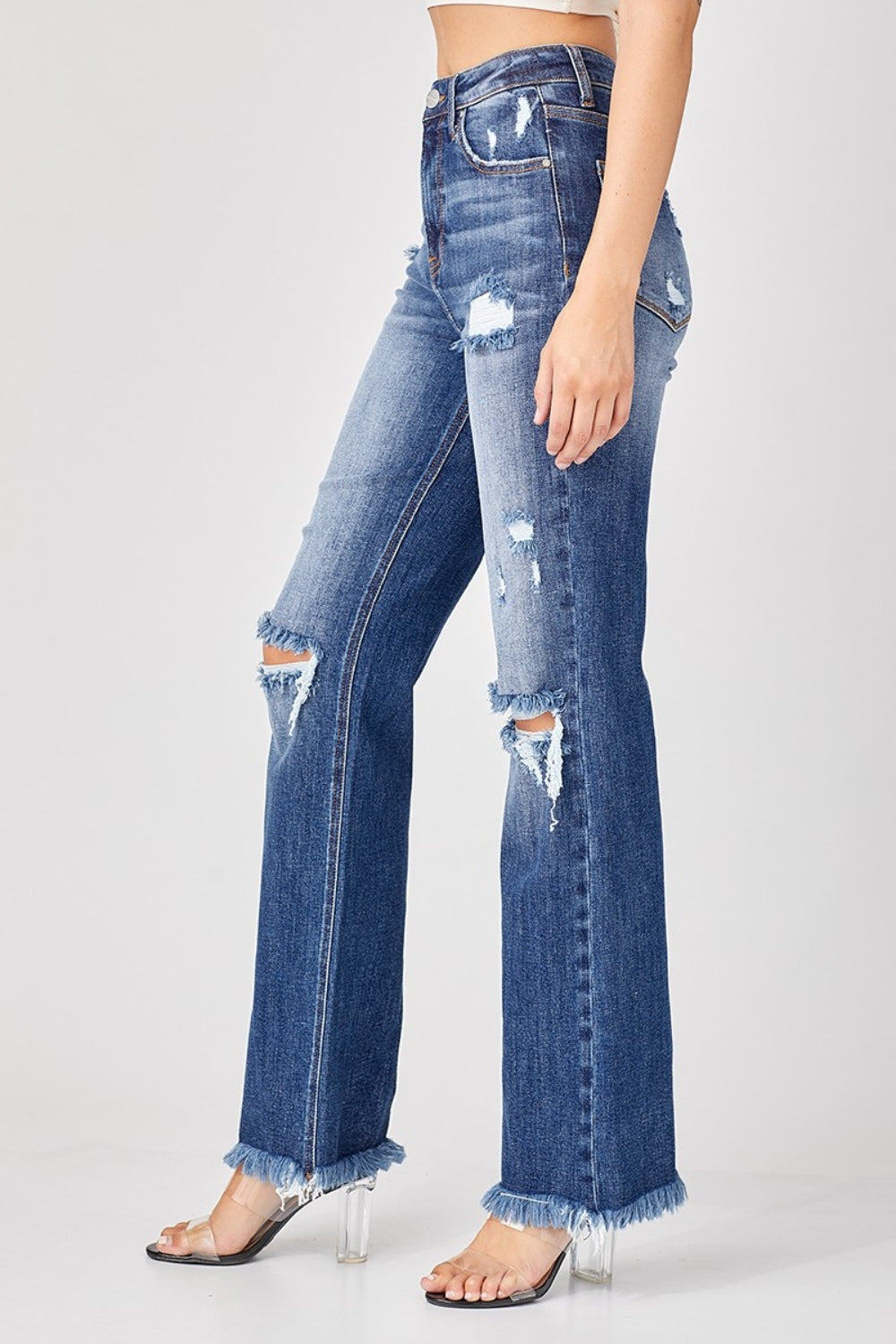 A person is wearing the Risen Full Size Raw Hem Distressed Straight Jeans paired with clear heels.