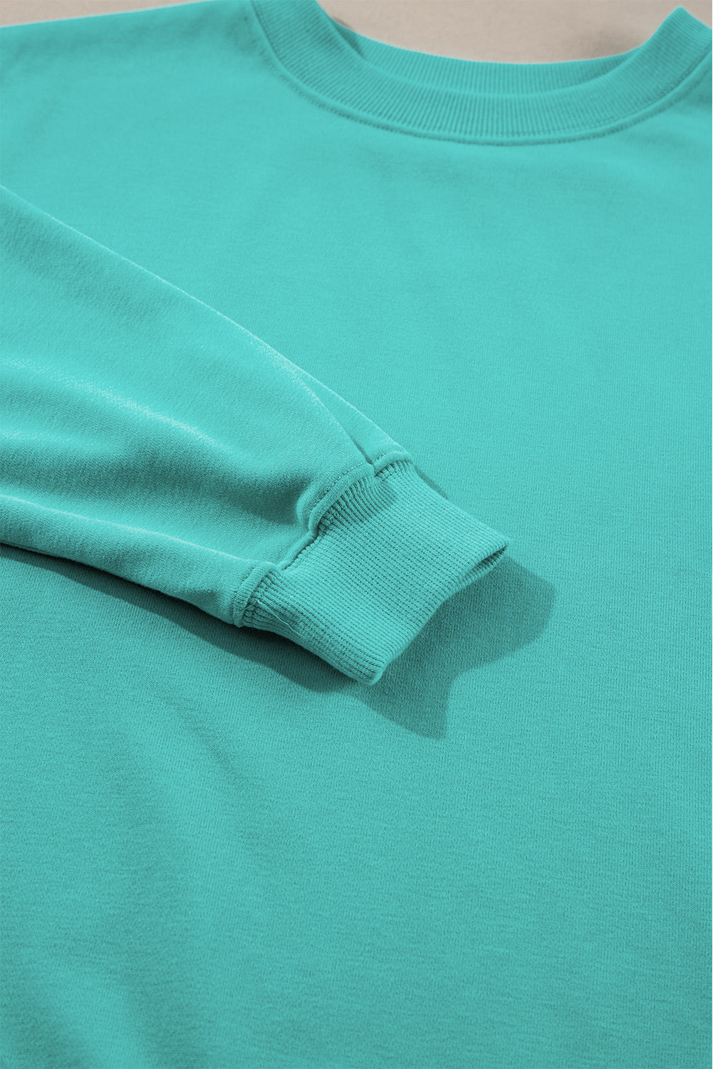 Person with long hair wearing an Aruba Blue Plain Drop Shoulder Crewneck Pullover Sweatshirt and carrying a floral crossbody bag, seen from the back, walking outdoors.