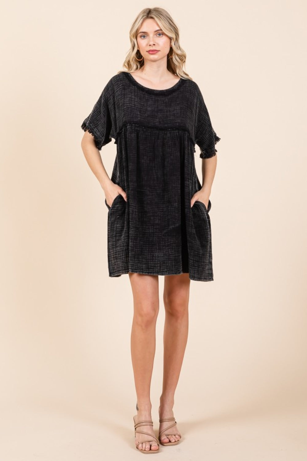 A person is wearing the Culture Code Full Size Short Sleeve Babydoll Texture Dress with Pockets, in black, standing against a plain background.