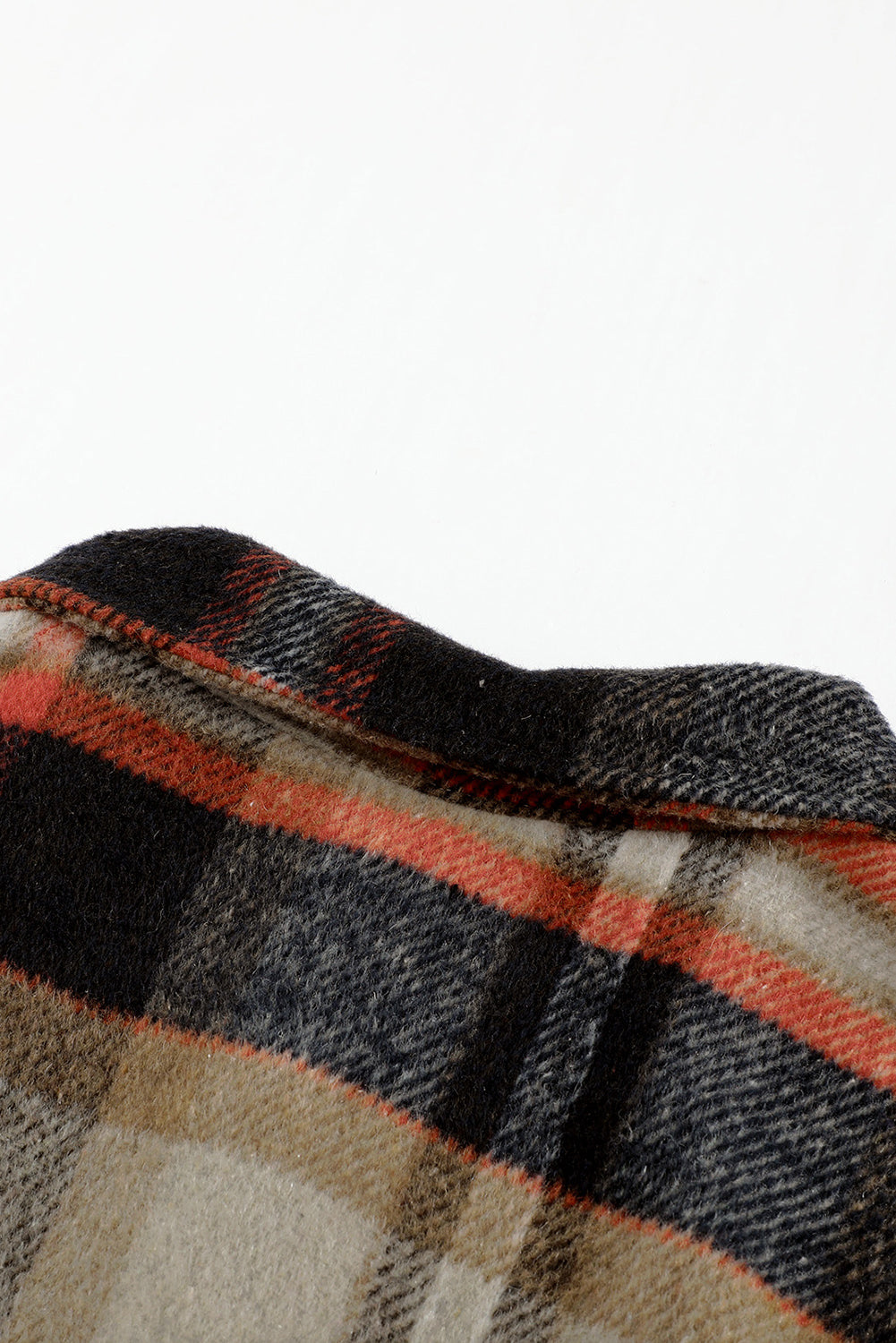 A person wearing a Brown Plaid Button Up Long Sleeve Flannel Shacket layered over a white top with ripped jeans and holding a brown handbag stands against a textured gray wall.