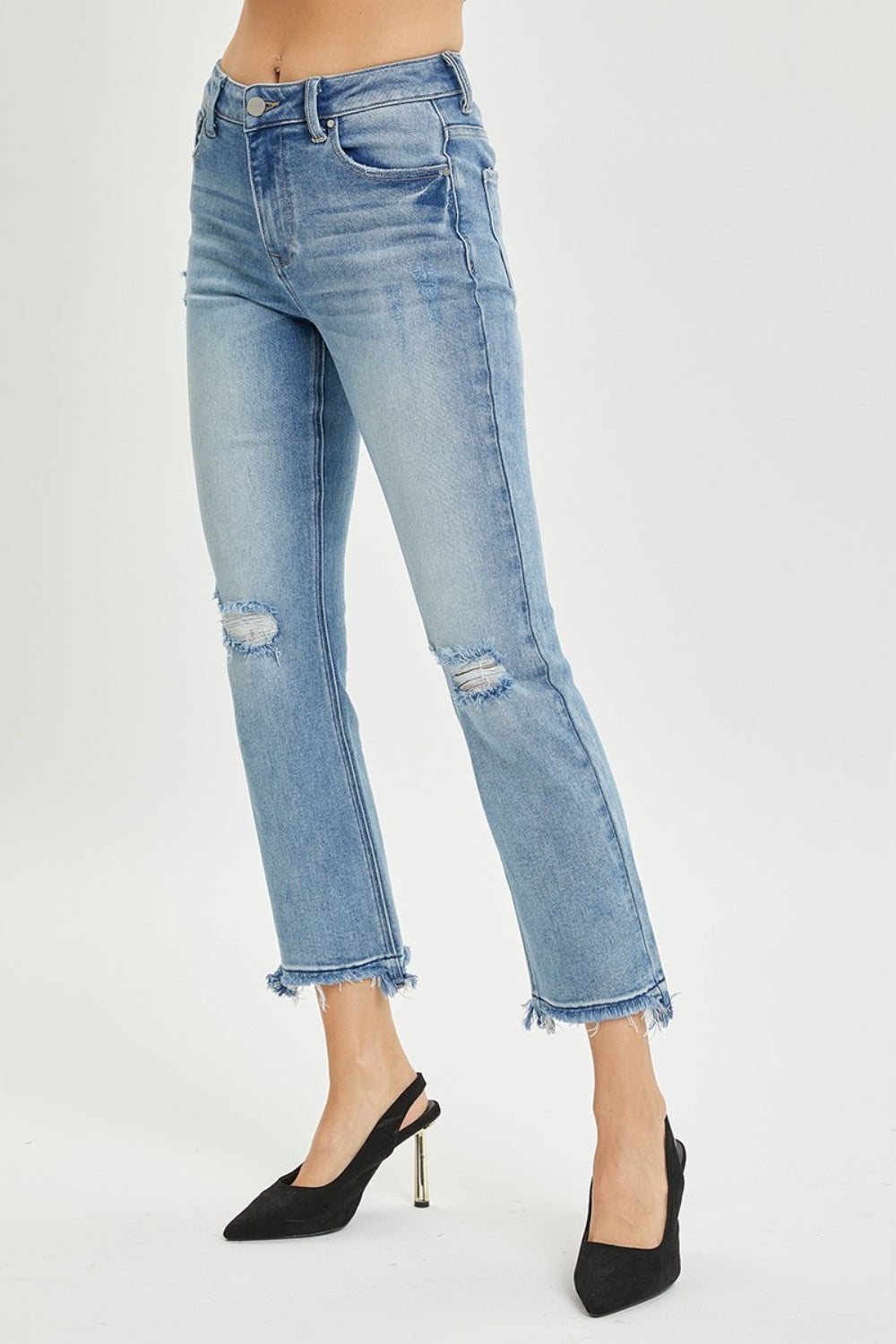 A person wearing the RISEN Full Size High Rise Distressed Cropped Straight Jeans in light blue with frayed hems, paired with black pointed-toe heels.