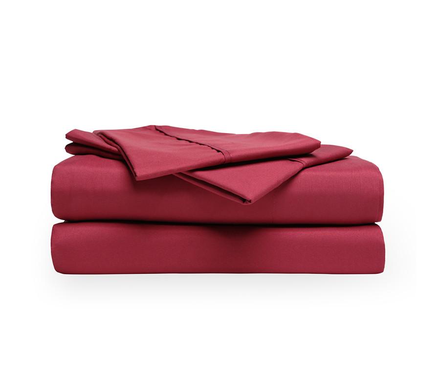 A stack of burgundy sheets made of soft fabric resting on a crisp white background.