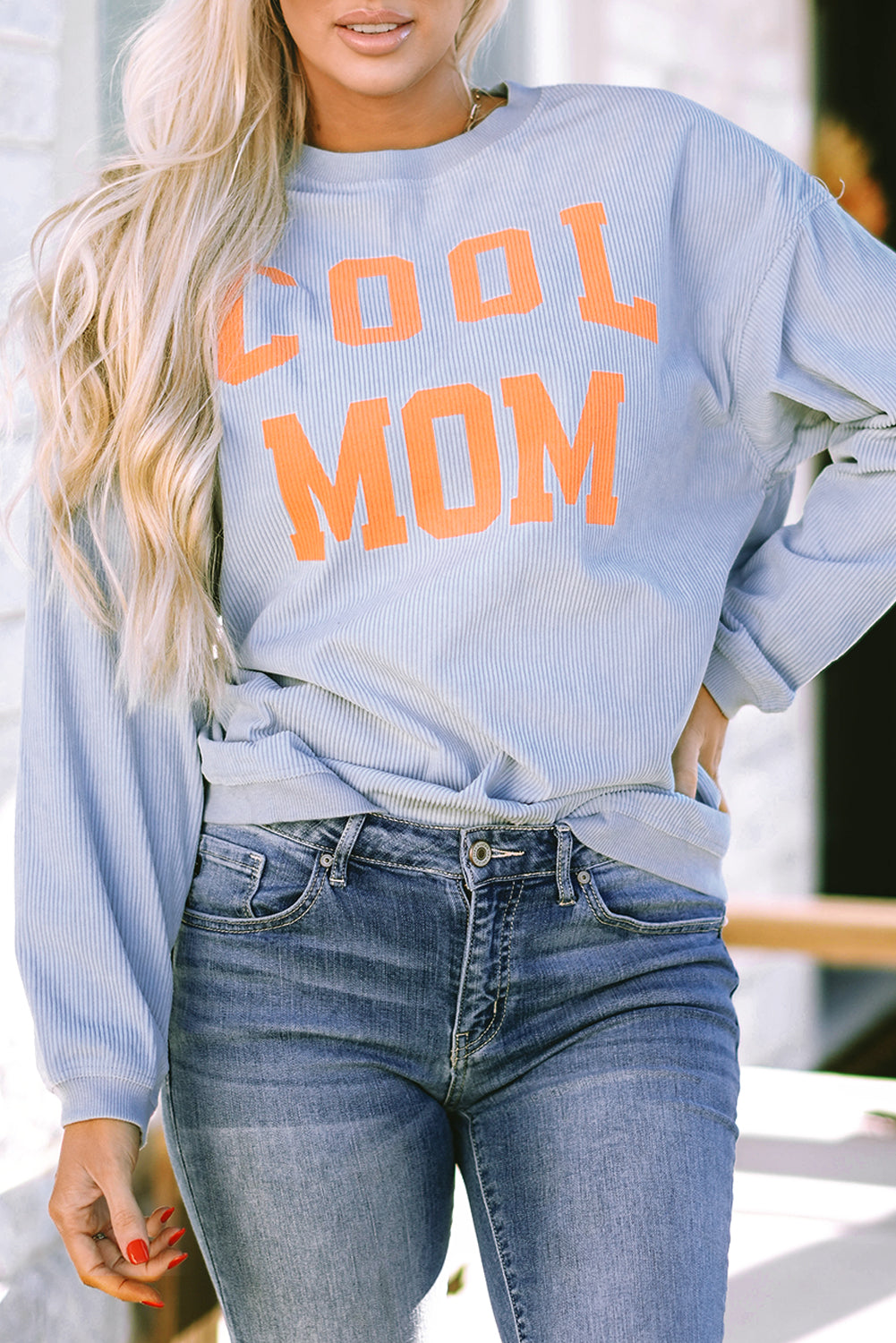 A person with long blonde hair stands facing away, wearing a Gray Cool Mom Graphic Print Cording Sweatshirt and blue jeans.