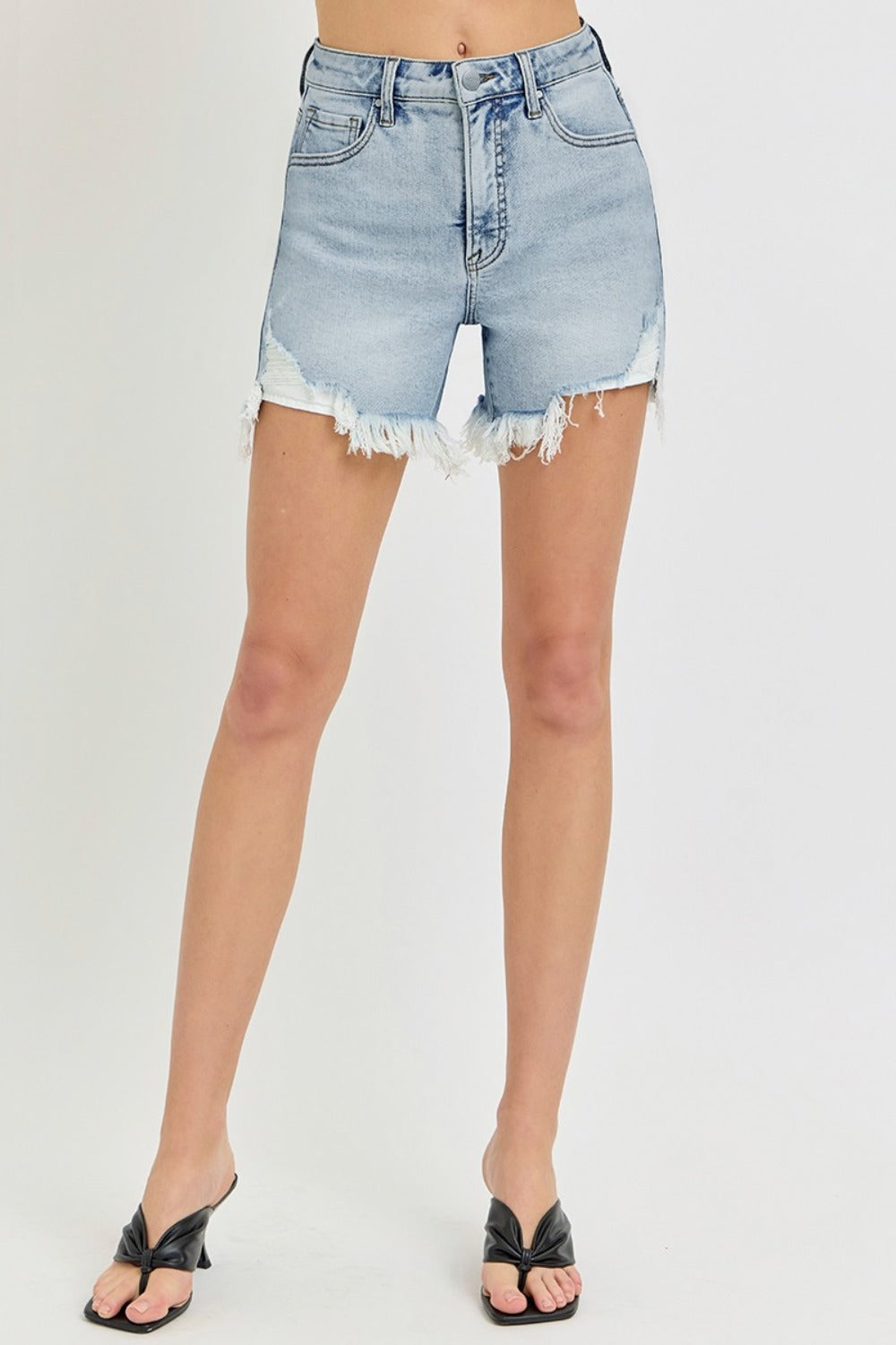 A person wearing the RISEN High Rise Side Step Hem Denim Shorts featuring light-wash, frayed hems, front pockets, and a versatile design.