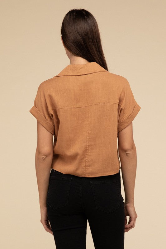 A woman with long hair is wearing the Always a Delight Short Sleeve Linen Top in brown and black pants, standing against a beige background.